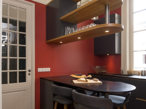 Cuisine d’artisan dans un appartement de Lyon 3° meubles blancs, et plan de travail en granit noir.